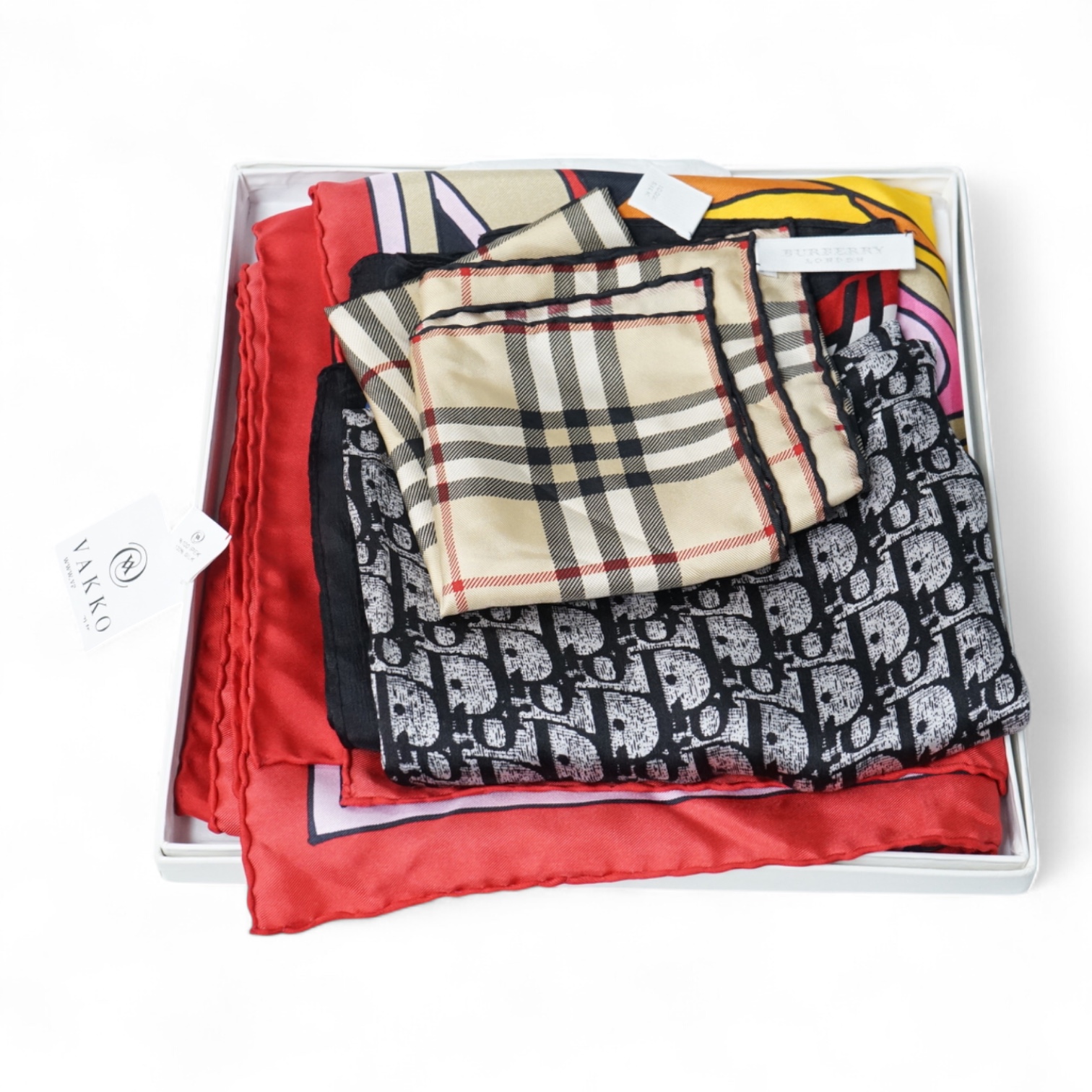 Three silk scarves comprising a Burberry check example, Christian Dior monogrammed and a Vakko abstract patterned example